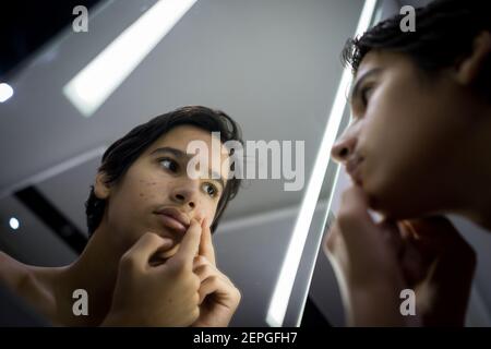 Teenager Junge überprüft seine Haut im Spiegel Stockfoto