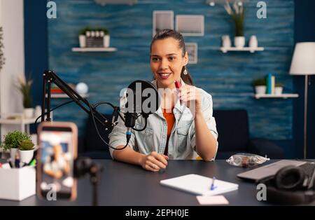 Berühmte Blogger Aufnahme roten Lippenstift Bewertung für Schönheit vlog. Frau vlogger macht live Make-up Tutorial teilen auf Social Media mit professionellen Mikrofon Blick auf Kamera für digitale Podcast Stockfoto