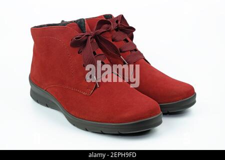 Rote Wildlederstiefel mit schwarzen Sohlen auf weißem Hintergrund. Damen Winterstiefel mit Schnürsenkeln. Wildlederschuhe mit Reißverschluss an der Seite auf weißem Hintergrund. Stockfoto