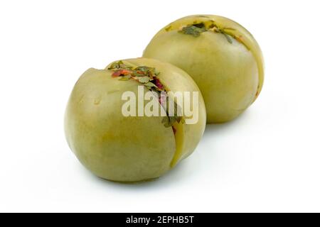Gefüllte grüne Tomaten auf einem weißen Teller. Eingelegte eingelegte Tomaten gefüllt mit Gewürzen und fein gehackter Petersilie. Leckere grüne eingelegte Tomaten. Stockfoto