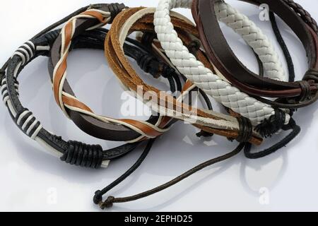 Steampunk Armbänder. Lederarmbänder in verschiedenen Farben auf weißem Hintergrund. Viele verschiedene Lederarmbänder. Stylische Hard Rock Accessoires. Stockfoto