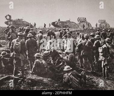 Männer der amerikanischen 30th Division in Ruhe mit deutschen Gefangenen nach der Gefangennahme von Bellicourt, 29. September 1918. Im Hintergrund sind britische Mark V Panzer (mit "Krippen" für die Überquerung von Schützengräben) des Bataillons 8th, Tank Corps, das eines von vier Bataillons der 5th Tank Brigade war, die der 5th Australian Division und American Corps für die Operation zugeteilt wurden. Stockfoto