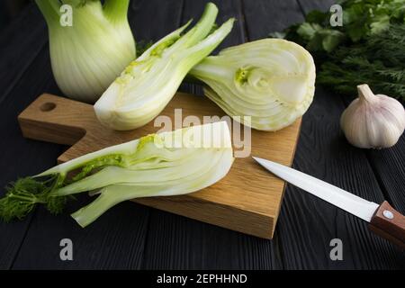 Fenchel in Scheiben auf dem Schneidebrett auf dem schwarzen Holz Hintergrund Stockfoto