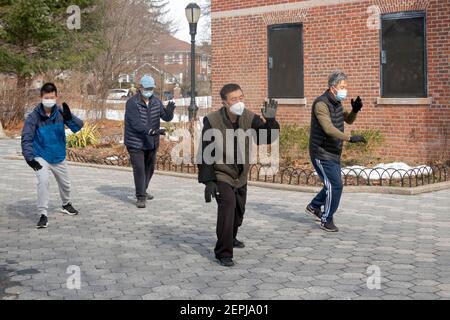 Vier chinesisch-amerikanische Männer unterschiedlichen Alters machen an einem kalten Wintermorgen Tai Chi Übungen. In einem Park in Queens, New York City. Stockfoto