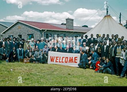 Eine bibelschulgruppe in Krugersdorp (KRUGERVILLE), Provinz Gauteng, Südafrika im Jahr 1962. Ein großes ‘Willkommensschild’ wird von den elegant gekleideten Anwesenden gehalten. Es gibt eine Rassenmischung in der Gruppe und ein großes Zelt (Festzelt) wurde benötigt, um die Versammlung unterzubringen. Der Fotograf interessierte sich damals besonders für christliche Kirchen-, Bildungs- und Missionsprojekte. Dieses Bild ist von einem alten Amateur 35mm Farbtransparenz. Stockfoto