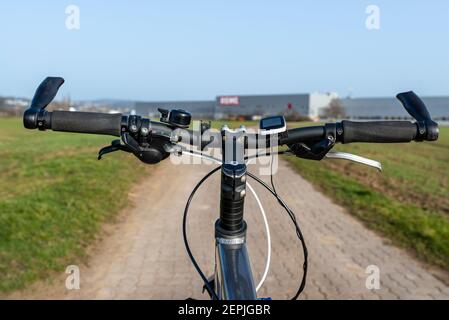 Mountainbike-Lenker aus der Perspektive der ersten Person gesehen. Sichtbarer Fahrradrahmen und Fahrradzubehör auf dem Lenker, und die Straße in der BA Stockfoto