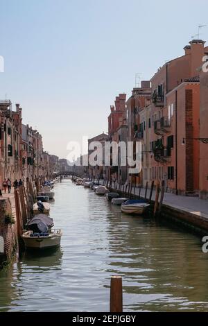 Bunte traditionelle venezianische Häuser in einem Kanal mit festleerenden Booten in Cannaregio - ruhiger Morgen mit leeren Straßen in Venedig, Venetien, Italien Stockfoto