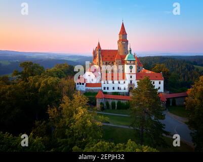 Schloss Bouzov. Aus der Vogelperspektive auf ein romantisches Märchenschloss in malerischer Hochlandlandschaft, vor rotem Abendhimmel. Tschechische republik. Stockfoto