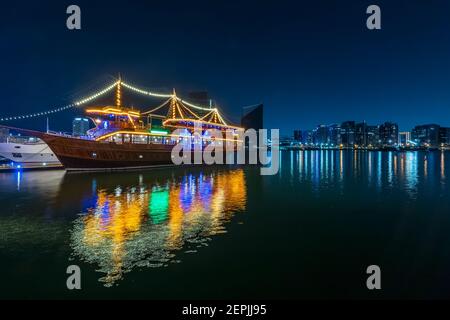 Dubai, VAE, 23. November 2020: Blick auf den Dubai Creek im alten Dubai in Al Seef. Wunderschön beleuchtete Dhau Kreuzfahrt angedockt mit einer atemberaubenden Reflexion auf dem w Stockfoto