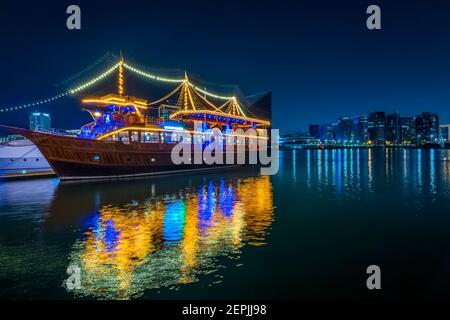 Dubai, VAE, 23. November 2020: Blick auf den Dubai Creek im alten Dubai in Al Seef. Wunderschön beleuchtete Dhau Kreuzfahrt angedockt mit einer atemberaubenden Reflexion auf dem w Stockfoto