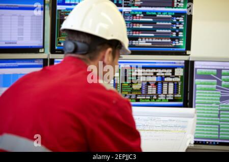 Zentralheizung. Thermometer an der Warmwasserzuleitung zum Heizsystem. Techniker trägt rote Jacke mit weißem Helm. Stockfoto