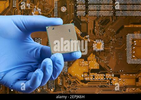 Techniker Person hält cpu-Zentralprozessor-Einheit über Leiterplatte Hintergrund. Hardware-Forschungskonzept Stockfoto