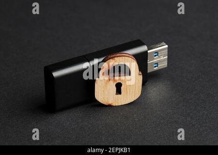 Digitale Sicherheit für elektronische Privatsphäre-Daten-Konzept. Dunkel launisch Foto. Schwarzer usb-Stick mit Holzschloss über mattem Hintergrund Stockfoto