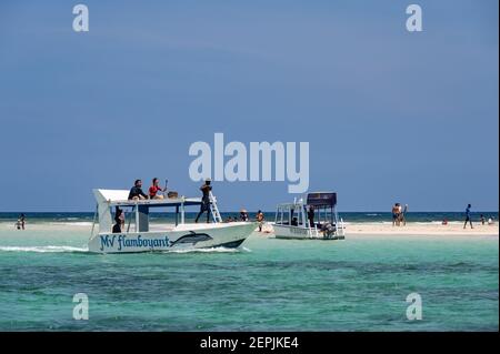 Ein Glasbodenboot, das von einer Ebbe-Sandbank mit Menschen auf dem Sand, Diani, Kenia, vertäut ist Stockfoto