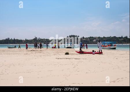 Ein Glasbodenboot, das von einer Ebbe-Sandbank mit Menschen auf dem Sand, Diani, Kenia, vertäut ist Stockfoto