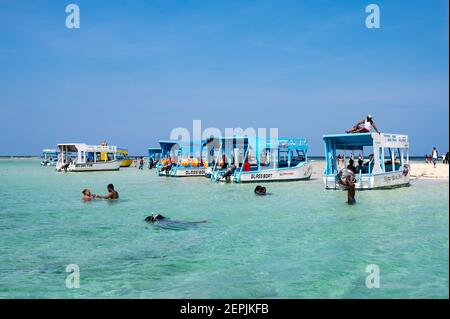 Ein Glasbodenboot, das von einer Ebbe-Sandbank mit Menschen auf dem Sand, Diani, Kenia, vertäut ist Stockfoto