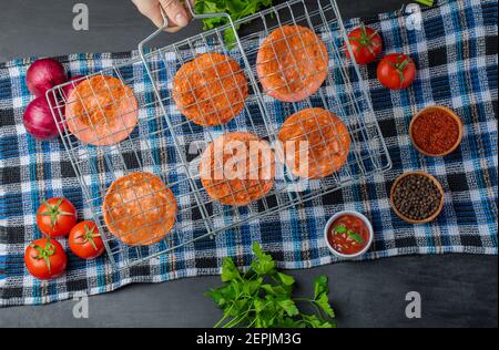Gegrillte Salami-Scheiben auf Grillrost über frischem Gemüse Stockfoto