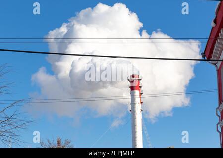 Rot-weiße Kamine des Kesselraums, ausgestattet mit einer Ampel. Weißer Rauch gegen blauen Himmel an sonnigen frostigen Wintertag Stockfoto