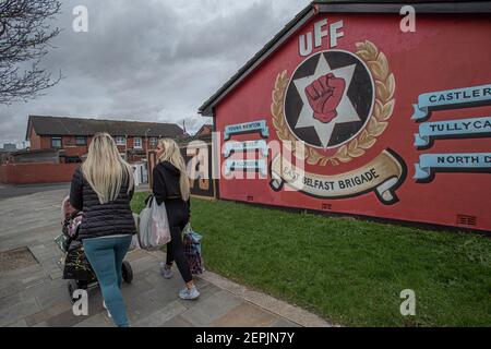 BELFAST, NORDIRLAND - Februar 24: Zwei Frauen gehen an Loyalisten-Wandgemälden in 'Freedom Corner', Newtownards Road, Belfast vorbei.hauptsächlich Pro der Arbeiterklasse Stockfoto