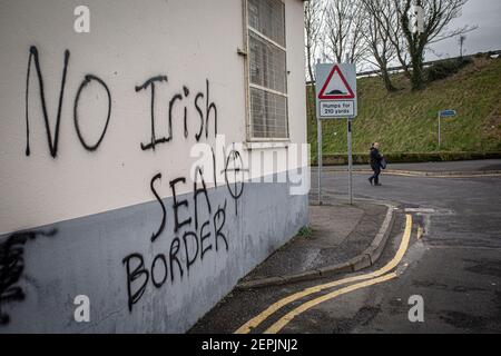 LARNE, NORDIRLAND - Februar, 24 : EIN Mann geht an drohenden loyalistischen Graffiti vorbei, das auf Hafenpersonal in Larne, Nordirland gerichtet ist. Hafeninspecti Stockfoto