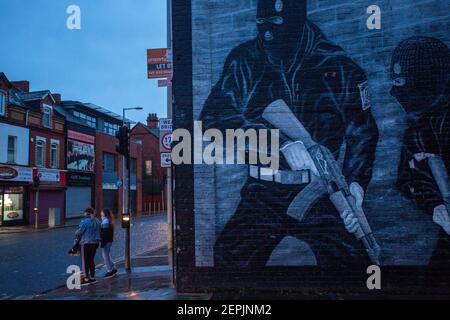 BELFAST, NORDIRLAND - Februar 23: Zwei Kinder, die am 23. Februar 2021 an einem loyalistischen paramilitärischen Wandgemälde auf der Newtownards Road vorbeigehen. Stockfoto