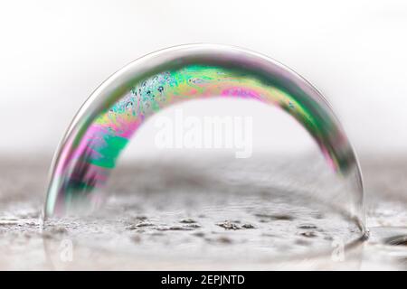 Seifenblase zeigt Regenbogenfarben auf einem nassen Untergrund Stockfoto