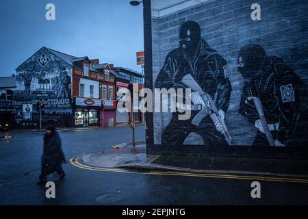 BELFAST, NORDIRLAND - Februar 23: Eine Frau kommt am 23. Februar 2021 in Belfast an einem loyalistischen paramilitärischen Wandgemälde auf der Newtownards Road vorbei. Stockfoto