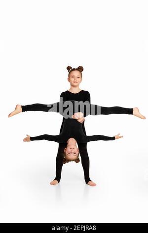 Zwei Turnerin Kindermädchen zeigen sportliche Fähigkeiten auf weißem Studio Hintergrund. Kinder zeigt Querfaden Stockfoto