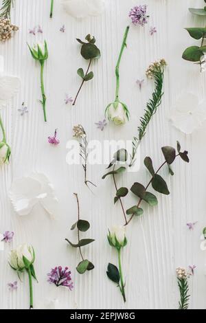 Stilvoller Flieder, Rosen und Eukalyptuszweige und Blumen Moderne Komposition auf weißem Holz flaches Lay, florales Muster. Hallo Frühling. Alles gute zum Muttertag und Stockfoto