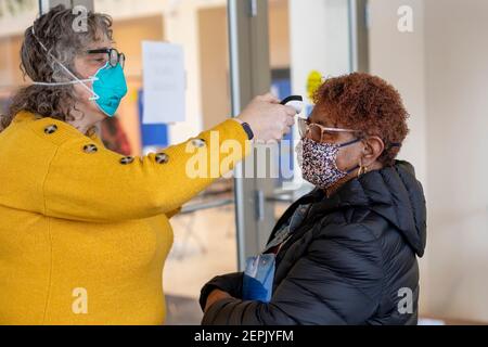 Detroit, Michigan, USA. Februar 2021, 27th. Eine Frau hat ihre Temperatur genommen, bevor sie eine der Covid-19 Impfkliniken des Detroit Health Department betritt. Kredit: Jim West/Alamy Live Nachrichten Stockfoto