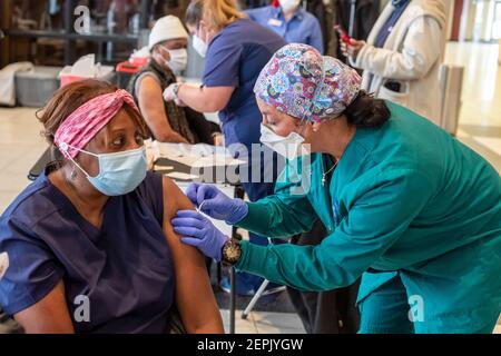 Detroit, Michigan, USA. Februar 2021, 27th. Joann Harrison ist auf eine Impfung gegen das Coronavirus in einer der Wochenend-Gemeinschaftskliniken des Detroit Health Department vorbereitet. Detroit erlitt zu Beginn der Pandemie eine unverhältnismäßig hohe Todesrate. Aber verfügbare Daten aus dem Bundesstaat Michigan zeigen, dass weiße Bewohner doppelt so wahrscheinlich sind, geimpft worden zu sein, wie Afroamerikaner. Kredit: Jim West/Alamy Live Nachrichten Stockfoto