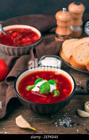 Borscht mit saurer Sahne und Basilikum auf braunem Hintergrund. Stockfoto