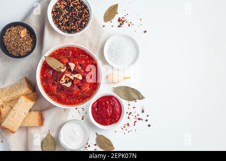 Rote Beete Suppe mit Knoblauch, Brot und Gewürzen auf weißem Hintergrund. Stockfoto