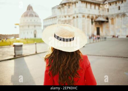 Von hinten Reisende Frau in Blumenkleid mit Hut Sightseeing auf der piazza dei miracoli in Pisa, Italien. Stockfoto