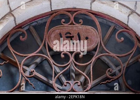 Ein halbkreisförmiges oberes Fenster mit stilisiertem Eisengitter und arabischer Ziffer, die das Baujahr eines Türdurchganges eines arabischen Hauses angibt, das 1948 im Viertel Musrara, das auch unter dem hebräischen Namen Morasha in West-Jerusalem Israel bekannt ist, aufgegeben wurde Stockfoto