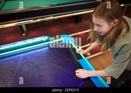 Tween Mädchen spielt Air Hockey im Entertainment Center. Stockfoto