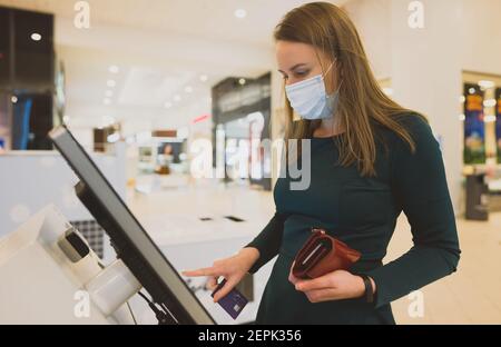 Frau, die ein Selbstbedienungsterminal im Einkaufszentrum benutzt. Stockfoto
