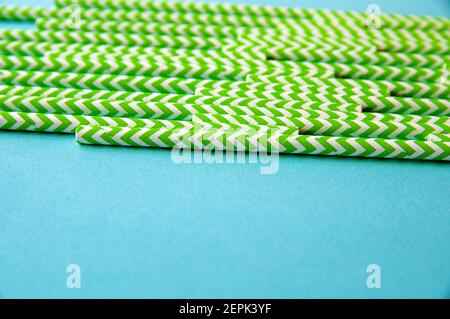Grüne und weiße Einwegstrohhalme sind auf einem angeordnet Hintergrund des blauen Papiers Stockfoto
