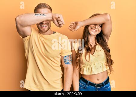 Junges Paar von Freundin und Freund umarmt und zusammen stehend Abdeckung Augen mit Arm lächelnd fröhlich und lustig. Blind Konzept. Stockfoto