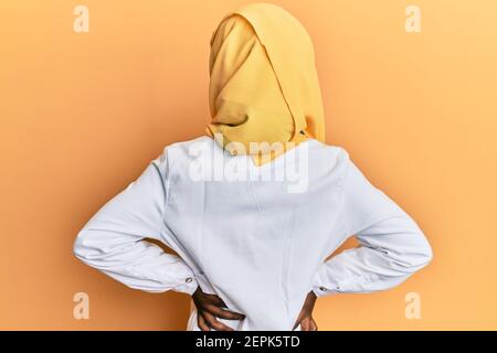 Schöne afrikanische junge Frau trägt Arzt Uniform und Hijab stehen Rückwärts und mit den Armen am Körper wegschauen Stockfoto