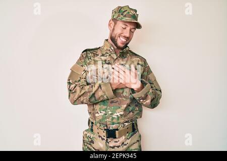 Junge kaukasische Mann trägt Tarnuniform Armee lächelnd mit Händen auf der Brust mit geschlossenen Augen und dankbare Geste im Gesicht. Gesundheitskonzept. Stockfoto