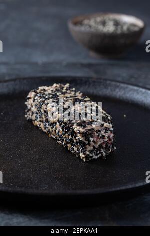 Gebratenes Thunfischsteak in schwarzem Sesam mit Spargel auf Schwarz Platte Stockfoto