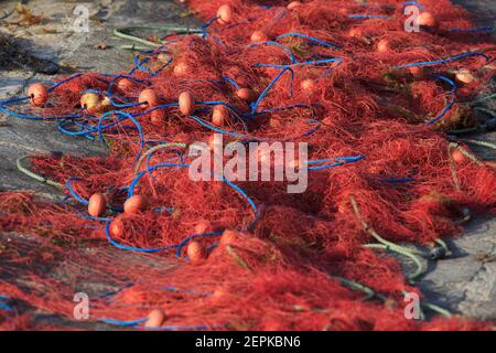 Rote Nylonfischernetze trocknen an Land in Marsaxlokk, Malta Stockfoto