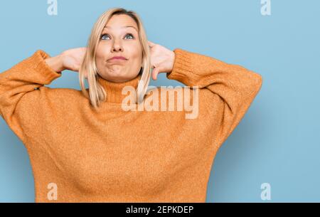 Mittlere kaukasische Frau trägt lässigen Winter Pullover entspannend und Stretching, Arme und Hände hinter Kopf und Hals lächelnd glücklich Stockfoto