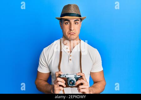 Hispanic junger Mann hält vintage Kamera deprimiert und sorgen für Not, Weinen wütend und Angst. Trauriger Ausdruck. Stockfoto