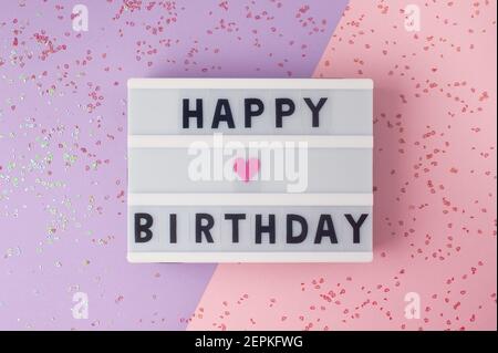 Happy Birthday - Text auf Display Leuchtkasten auf lila und rosa Hintergrund. Stockfoto