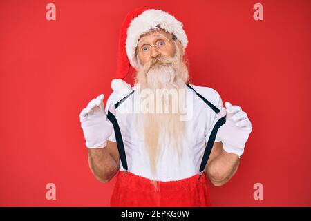 Alter älterer Mann trägt weihnachtsmann Kostüm mit Hosenträger ahnungslos und verwirrt Ausdruck. Zweifel Konzept. Stockfoto