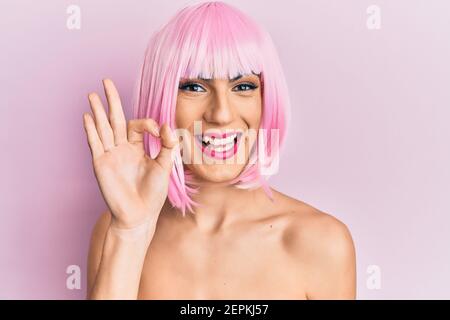 Junger Mann trägt Frau Make-up trägt rosa Perücke lächelnd positive tun ok Zeichen mit Hand und Fingern. Erfolgreicher Ausdruck. Stockfoto