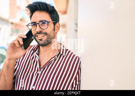 Junge gutaussehende hispanischen Mann mit Bart lächeln glücklich im Freien sprechen Am Telefon Stockfoto