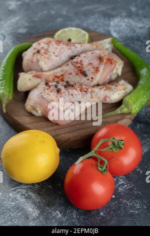 Vertikale Foto von frischen Bio-Tomaten und Zitrone mit rohen Hähnchenbeine Stockfoto